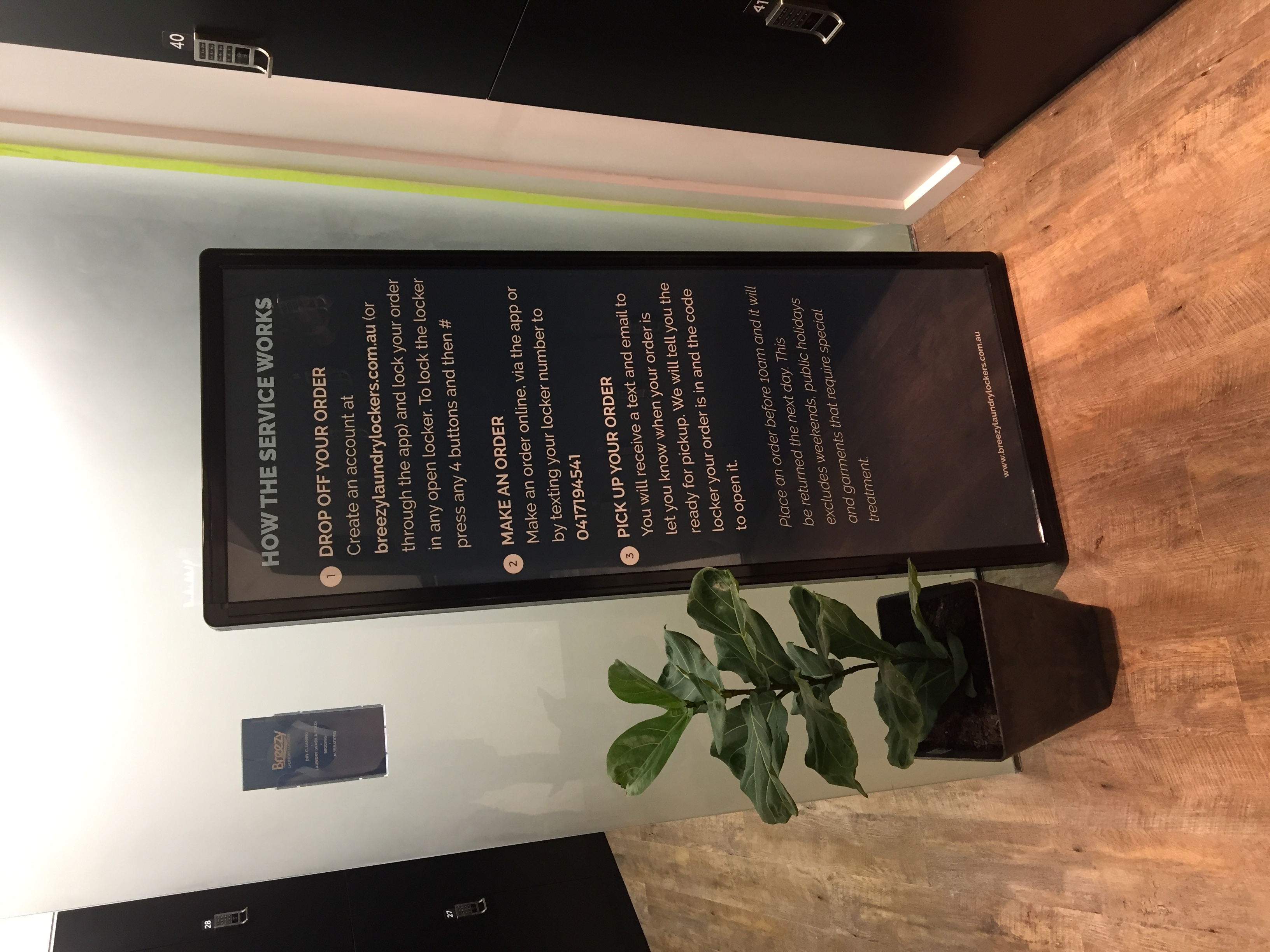 The How The Service Works floor-standing customer instruction sign explaining drop off, make an order, and pick up steps