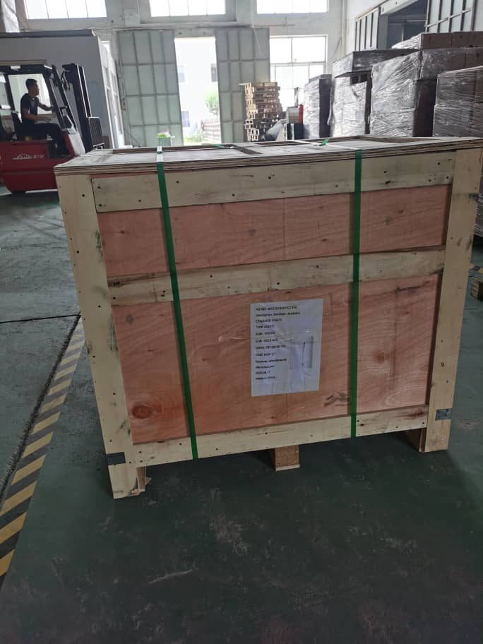 New purpose-built plywood shipping crate for a Breezy Laundry Lockers order, banded with green strapping at the factory floor before international export. Replaces the cardboard packaging that previously caused damage in transit.