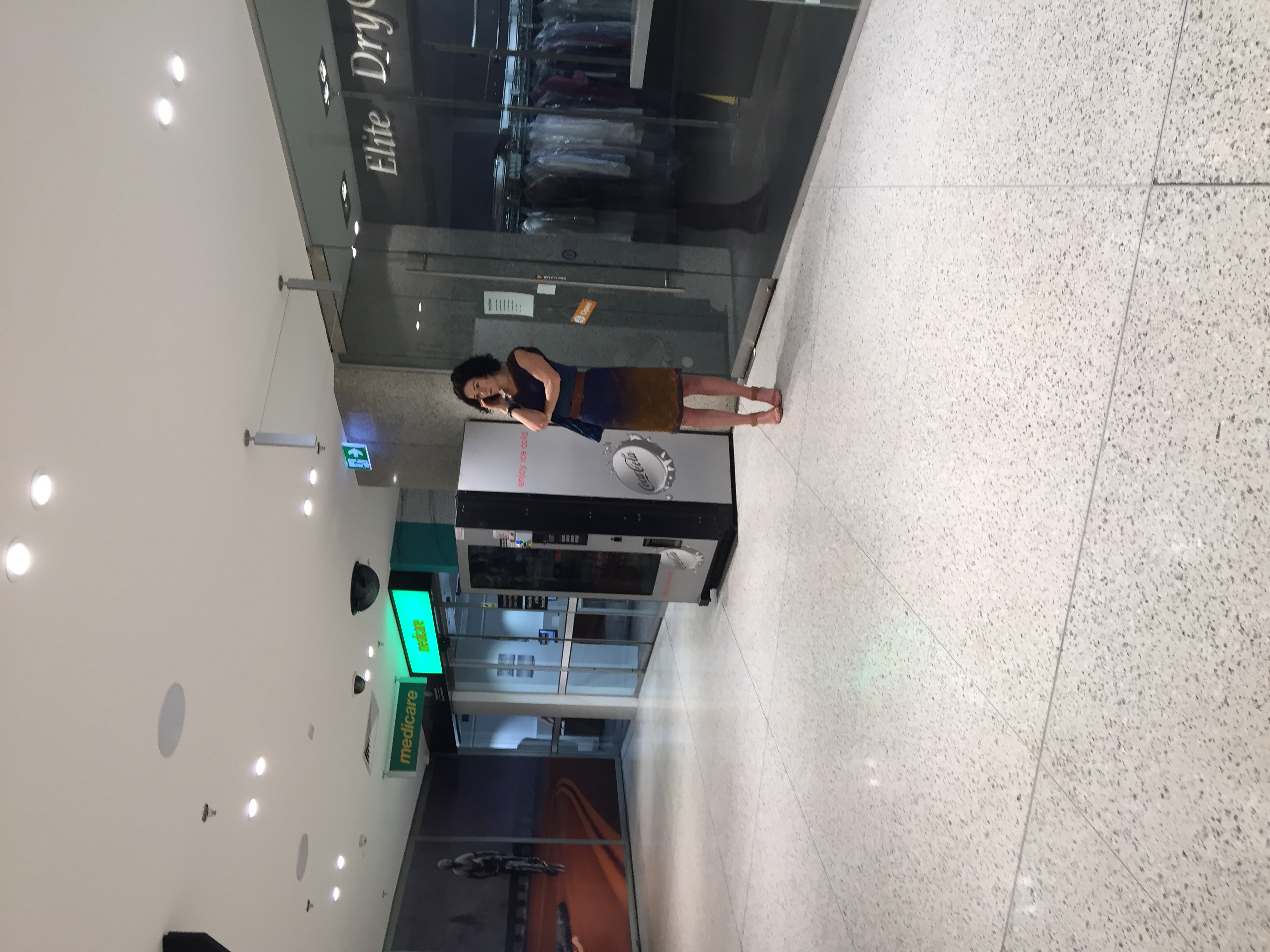A frustrated customer standing on the phone outside the closed Elite Dry Cleaners shopfront, locked out because the staffed counter is on a break